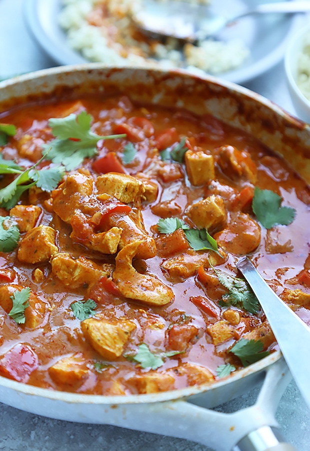 Butter chicken simmering in thick tomato cream sauce with cilantro in a large skillet